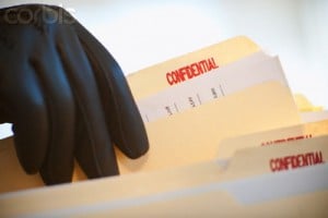 A gloved hand taking confidential files